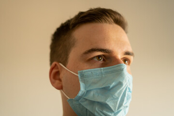 Ein Junger weißer Attraktiver Mann mit Maske schaut zur Seite, Junger Mann mit Maskenschutz