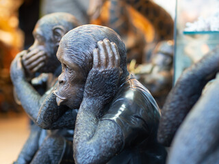Statue of monkey holding hands on ears.