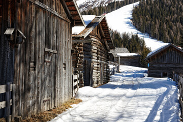 Fototapeta na wymiar Old wooden huts in a mountain forest in late winter, Alps, Europe