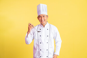 smiling male chef holding a ladle about to taste food on isolated background