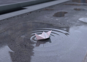 Origami. Paper boat on a puddle