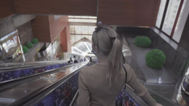 Blond hair woman walking down the escalator 4K stock footage