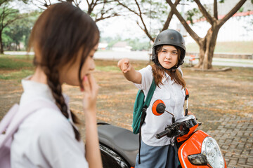 Obraz premium Student girl on motorbike pointing finger because of problem with student girl