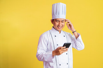 asian male chef wearing chef jacket using a smartphone on isolated background