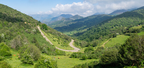 Vistas panorámicas del paisaje del Valle de Somiedo en Asturias, con carreteras serpenteantes atravesando montañas verdes, al fondo un cielo azul con nubes blancas en un entorno natural, verano 2021 