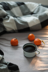 Winter cozy concept. Cup with coffee and tangerines on the bed. Copy space. Flat lay, top view
