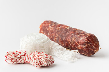 Sausage casing and cotton string roll for butchers. Elastic netting for roasting, boiling or smoking cold meat. Salami sausage on the white background.