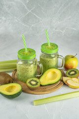Healthy green smoothie made from fresh vegetables and fruits, on a light background. Detox drinks made of avocado, kiwi, apple, celery in stylish glass glasses. Proper nutrition,  healthy lifestyle