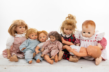 Collection of multiple dolls sitting on a rough white wooden table isolated on white with copy space