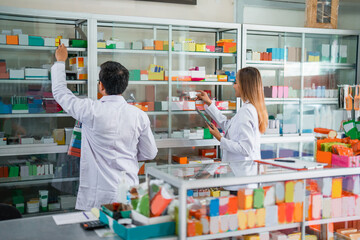 two pharmacists in uniform composing medicine on a display case in a drugstore