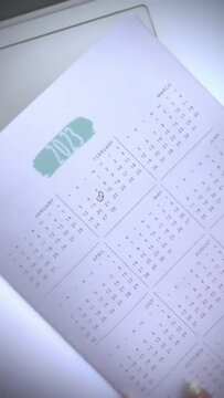 2023 year calendar with a female hand pointing important dates in a black pen