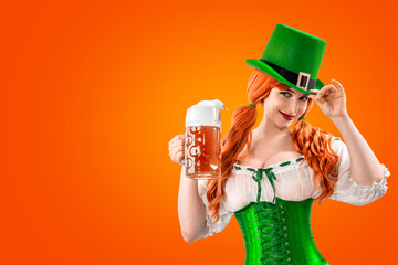 Happy Irish girl holding big mugs with beer or ale. Young red-haired woman аs green Leprechaun elf...