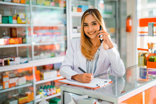 beautiful pharmacist smiling for the camera when receiving a call while working at the pharmacy