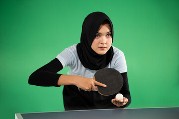 Asian veiled female athlete preparing to serve while playing ping pong