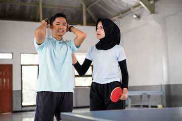 Fototapeta na wymiar Veiled female ping pong athlete motivates male partner down with match result