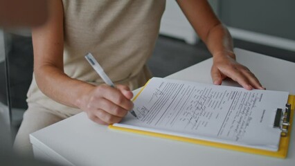 Woman hands signing papers sitting at table close up. Girl writing documents.