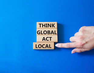 Think global act local symbol. Wooden blocks with words Think global act local. Businessman hand....
