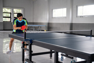 Asian male ping pong player ready to receive service ball in ping pong match