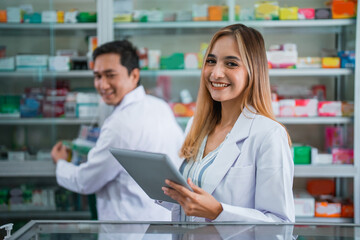 Attractive asian female pharmacist in uniform working using digital tablet in pharmacy