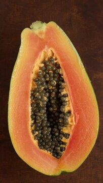 Fresh papaya fruit half moving left and right. Seamless loop. Vertical video.