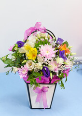 Beautiful tender bouquet of flowers in white box on wooden background with space for text