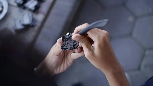 Details of the process of cleaning traces of paint on craft pins made of acrylic and colored using enamel paint, this process uses cutting pens, brushes and rags which are all handmade in a workshop