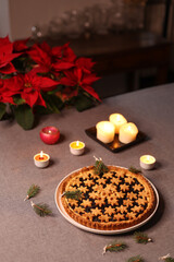 view from above of festive tart on grey table cloth and light of candles