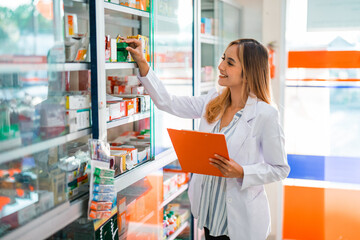 female pharmacist in uniform working checking medicine by observing the medicine package at the pharmacy - Powered by Adobe