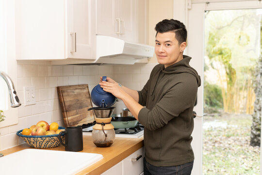 Chinese American man prepares coffee in the kitchen.
