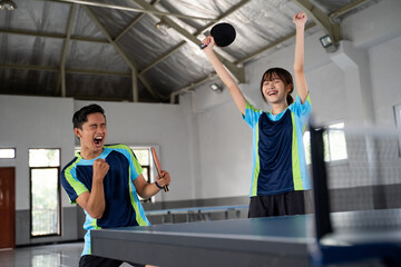 male and female ping pong doubles players excited during a ping pong match