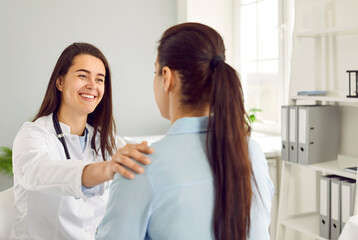 Happy female doctor congratulates her patient on recovery and reports good test results. Friendly...