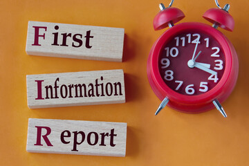 FIRST INFORMATION REPORT - words on wooden blocks on orange background with red clock