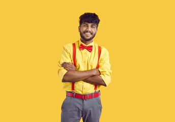 Studio portrait of smiling man in party outfit. Happy young Indian guy in yellow shirt, gray pants,...