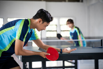 Male athlete carrying a ball and paddle while serving a ping pong game at a ping pong table