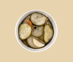 Pickled sliced cucumbers in brine in a bowl on yellow background. Traditional meat snacks. Healthy fermented food.