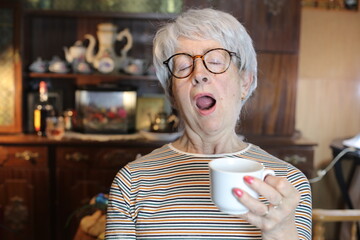 Senior woman sleeping while drinking coffee 