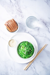Green seaweed spicy salad with sesame seeds in a bowl