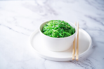 Green seaweed spicy salad with sesame seeds in a bowl