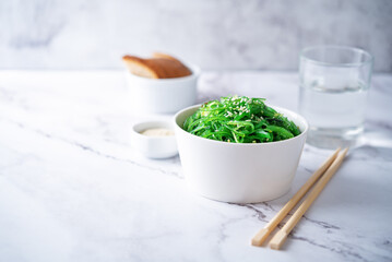 Green seaweed spicy salad with sesame seeds in a bowl