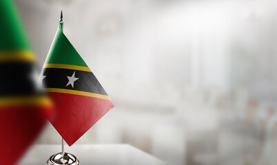 Small flags of the Saint Kitts and Nevis on an abstract blurry background