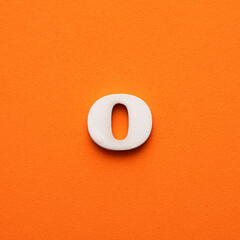 White lowercase letter o on orange foamy background