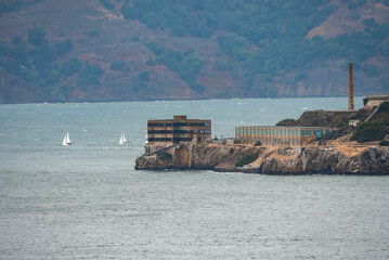 Distant view of old buildings on Alcatraz Island amidst San Francisco Bay with mountain in the...