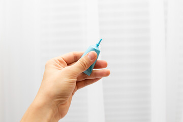 A woman's hand holds a small blue tube with a cream sampler. Free sample of cosmetics