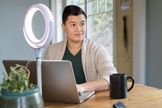 Asian American trans man working on a laptop.