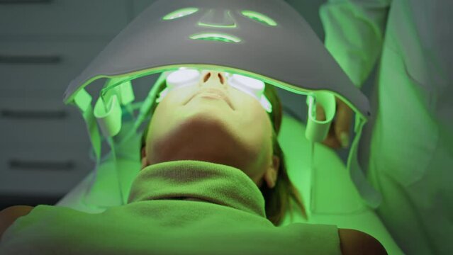 Woman lying phototherapy clinic close up. Beautician checking led light mask.