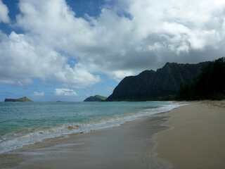 Gentle wave lap on Waimanalo Beach looking towards Rabbit island and Rock island on a nice day with clouds in the sky