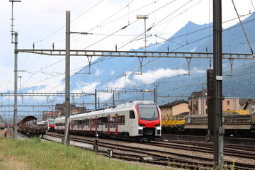 Swiss Train traveling on Railways. Mountains in background.
