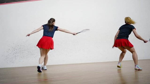 Female athletes compete in skill by playing squash