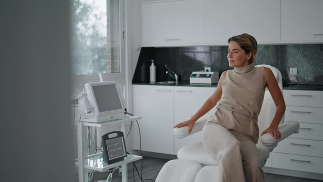 Woman sit cosmetology chair waiting for professional skincare consultation.
