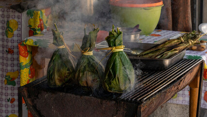 Fototapeta na wymiar typical food of the jungle. charcoal grilled meat inside banana leaves